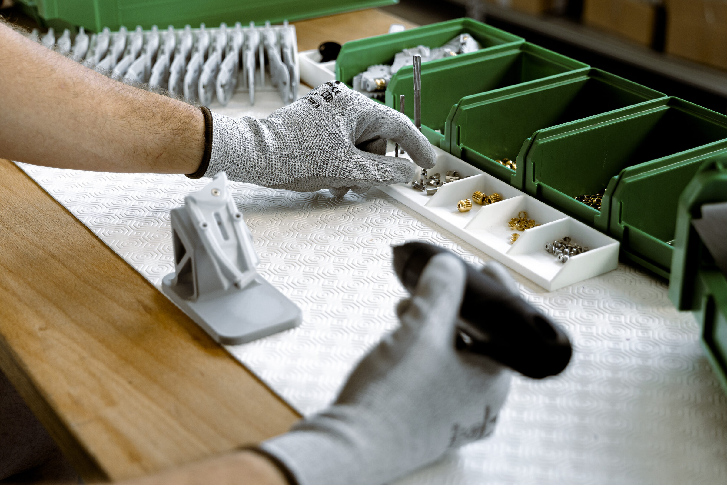 Manual assembly of mechanical components with green trays on the line